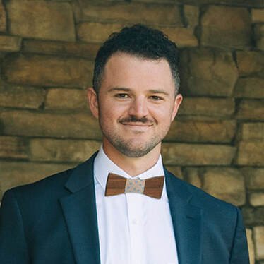 Cameron Zamot standing in front of a brown brick background