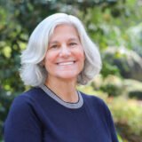 Christine Kushner smiling in front of a green nature background.