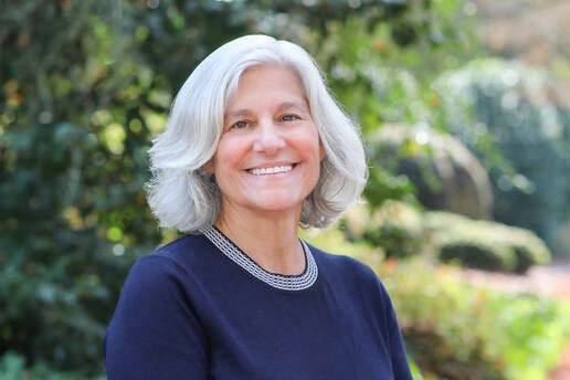 Christine Kushner smiling in front of a green nature background.