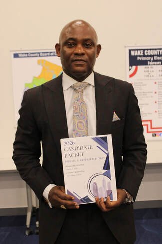 Robert Mitchener in a suit holding a book.