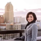 Sana Siddiqui standing on a balcony with the Raleigh skyline behind