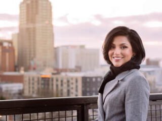 Sana Siddiqui standing on a balcony with the Raleigh skyline behind
