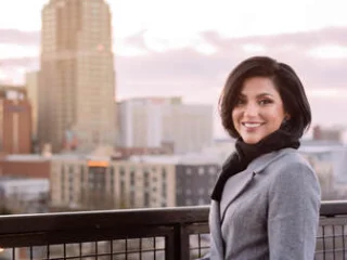 Sana Siddiqui standing on a balcony with the Raleigh skyline behind