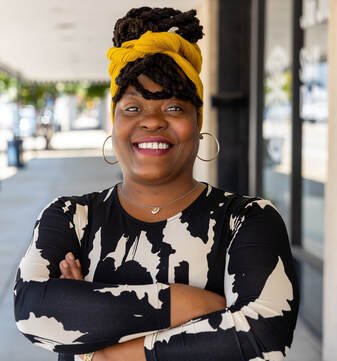 Tolulope Omokaiye standing with arms folded in front of a store.